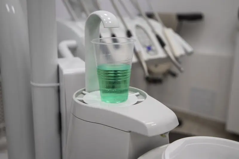 a cup of mouth rinse sitting on a sink in a dental office